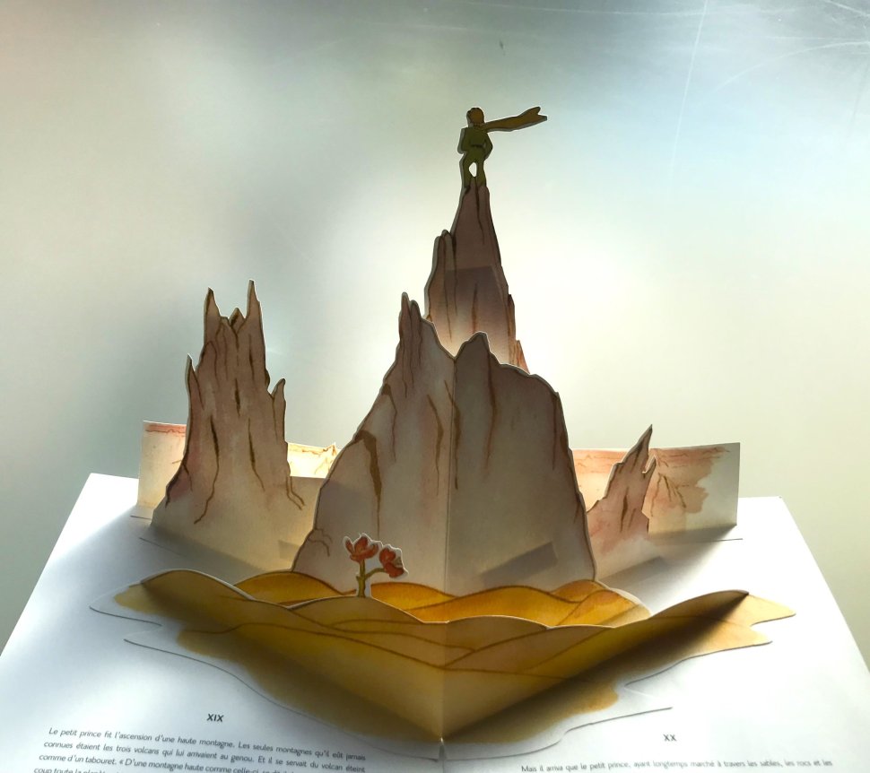 Papierowy trójwymiarowy wizerunek chłopca na szczycie góry.